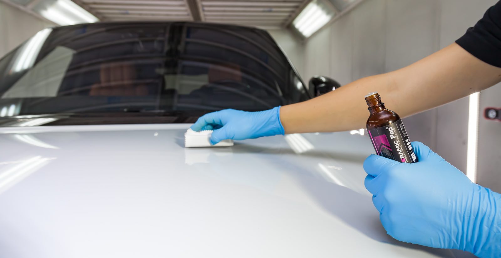Novosibirsk, Russia - 08.01.2018: The process of applying a nano-ceramic coating Ceramic Pro 9h and Light on the car's hood by a male worker with a sponge and chemical composition to protect the paint